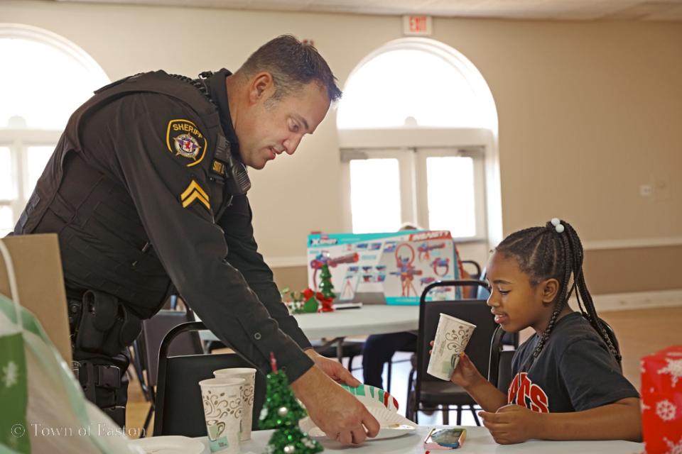 Cpl. Jeff Smith helps his new friend wrap her gifts after participating in the Talbot Optimist&#039;s &#039;Shop with a Cop&#039; event.